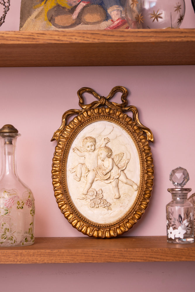 Antique ceramic angels in a gold oval frame