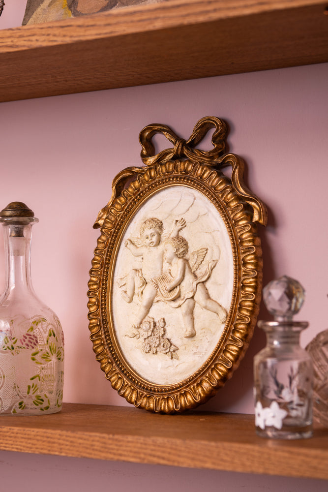 Antique ceramic angels in a gold oval frame